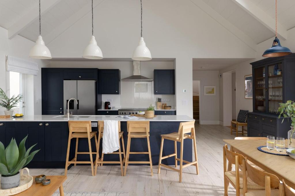 a kitchen with blue cabinets and a large island with bar stools at Brennik House in Port Isaac