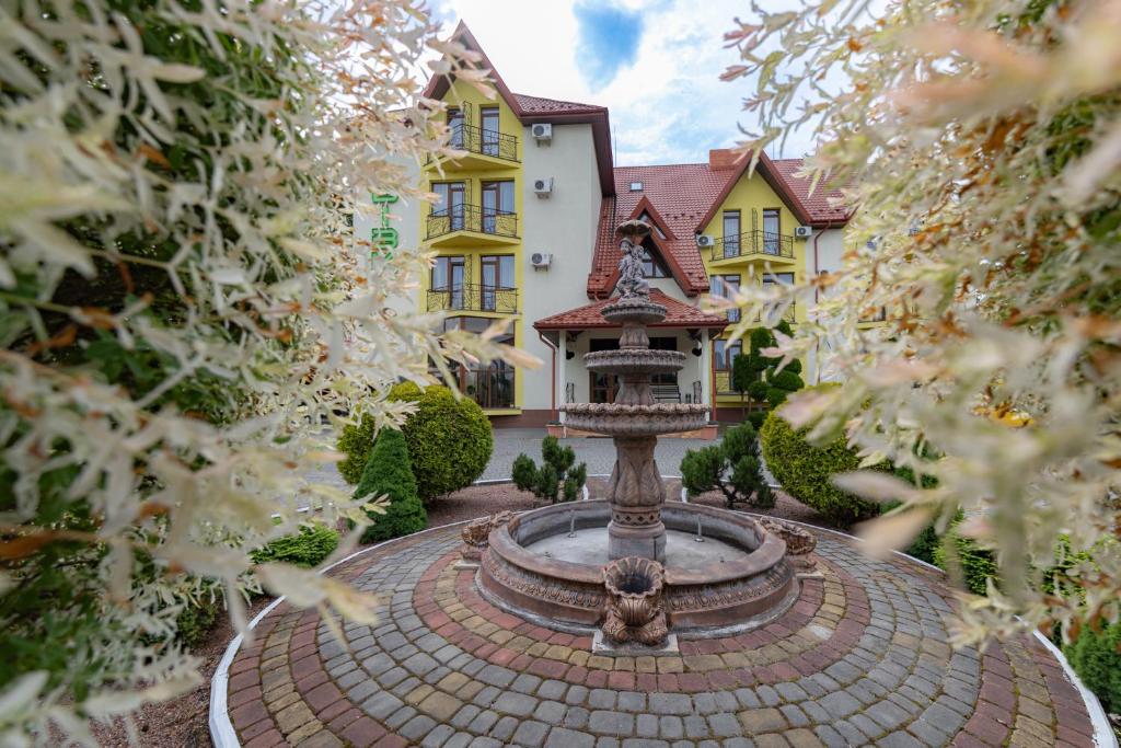 a house with a fountain in front of a building at Hotel Restaurant Vizit in Truskavets