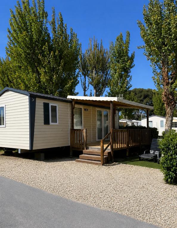 a tiny house with a porch and a deck at Mobil Home SIBLU VALRAS PLAGE in Sérignan