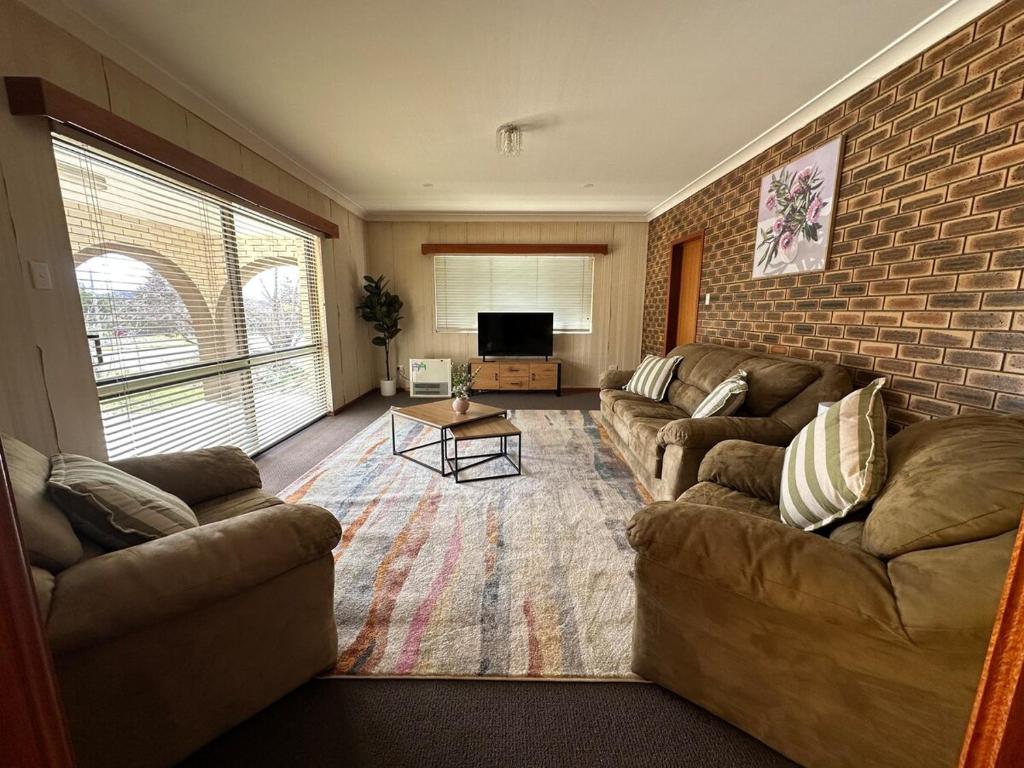 a living room with two couches and a brick wall at Casa Sarina in Stanthorpe