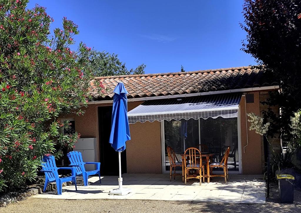 a blue umbrella on a patio with chairs and a table at les lauriers in Saint-Sernin