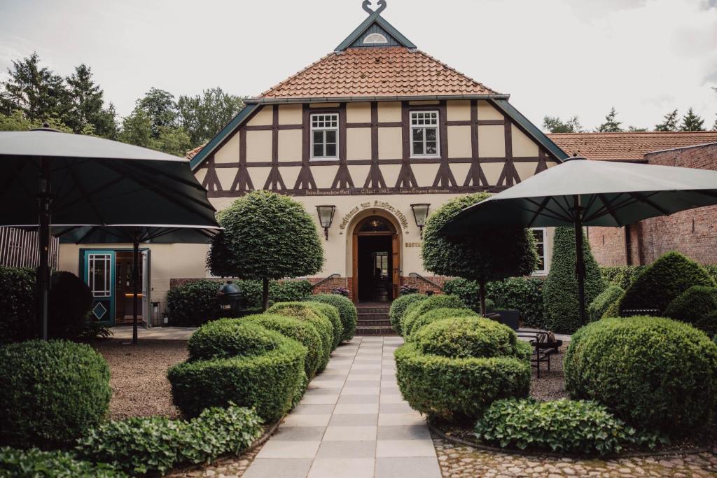 a large house with bushes and umbrellas in front of it at Klostermühle in Groß Meckelsen