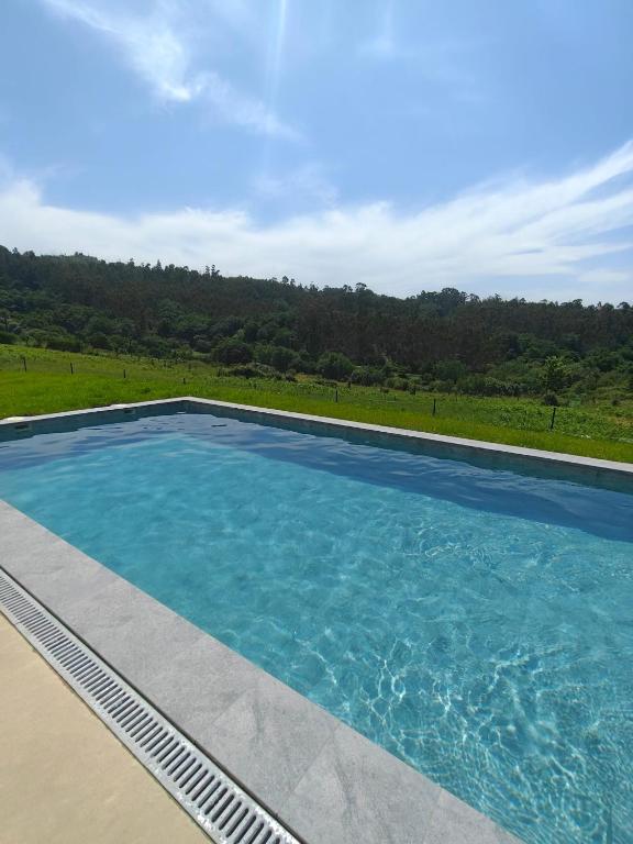 a large swimming pool with blue water at A casa das Ías in Tourón
