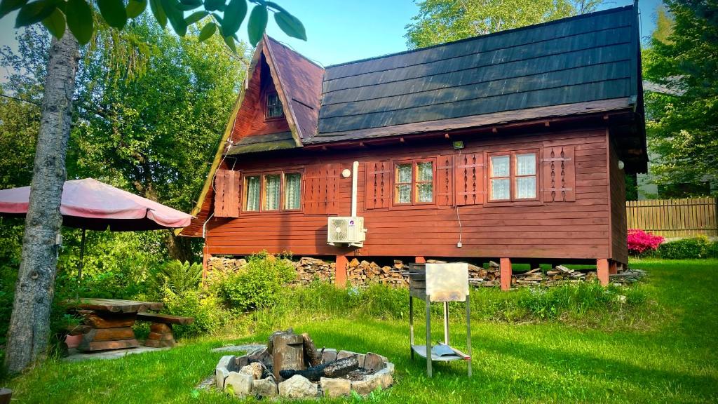 a wooden house with a fire place in front of it at Leśny Zakątek Nowy Wiśnicz in Nowy Wiśnicz