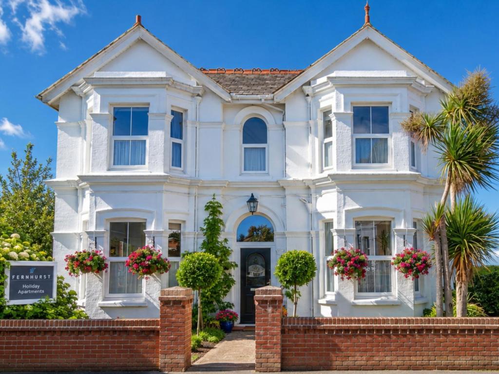 a white house with a brick fence at Fernhurst holiday apartments in Shanklin