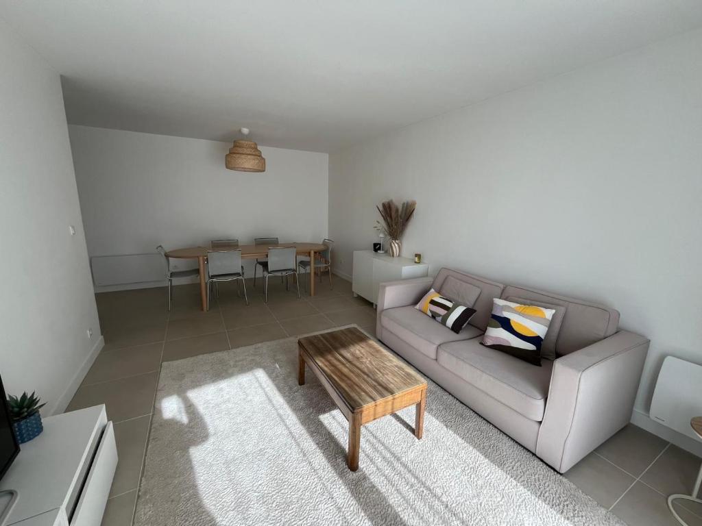 a living room with a couch and a table at Appartement avec piscine chauffée et Tennis proche Deauville in Touques