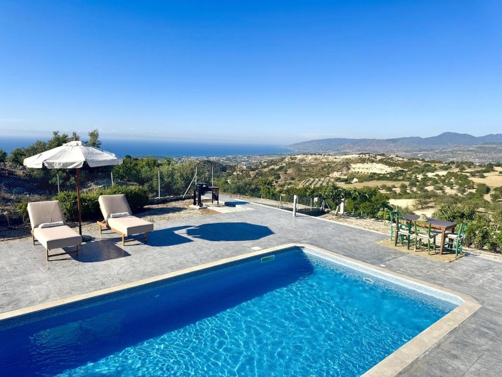 a swimming pool with two chairs and an umbrella at Villa Tuludis in Drousha