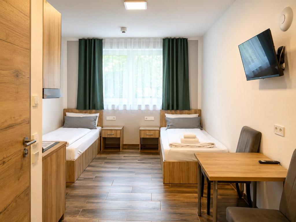 a small room with two beds and a table at Boardinghouse MDS in Aschheim