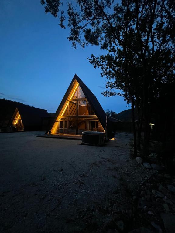a glass house with a lit up facade at night at A-frame Boema in Cîmpu lui Neag