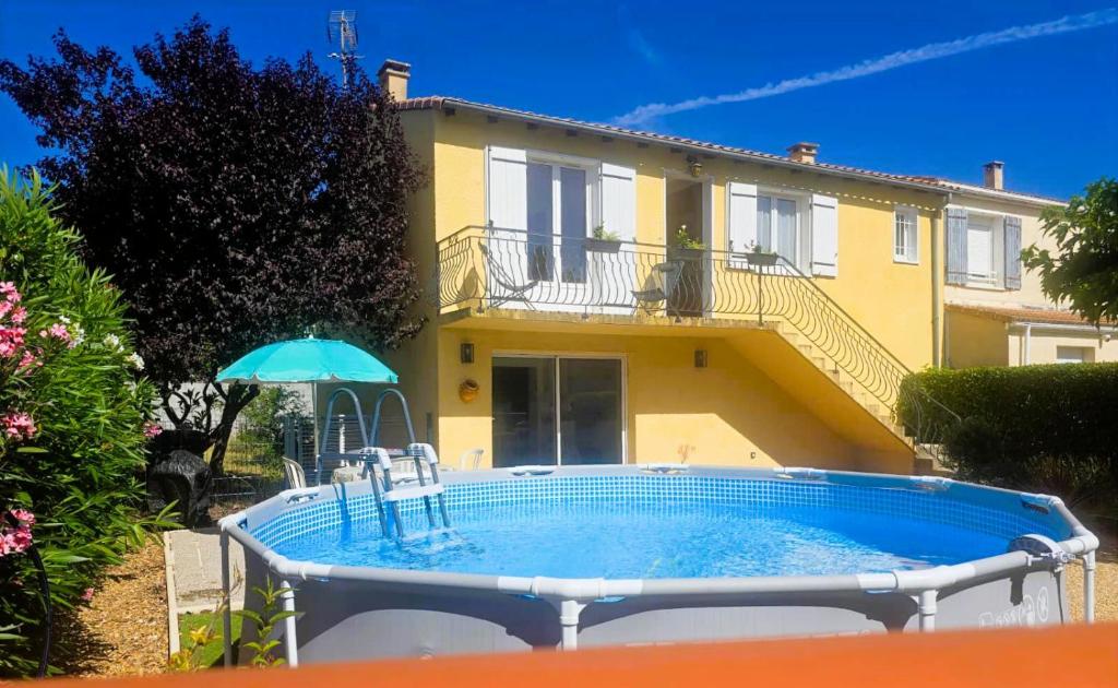 a pool in front of a house with an umbrella at Le Balcon de Cournon, piscine, jardin, clim à 15 min de plages in Cournonterral