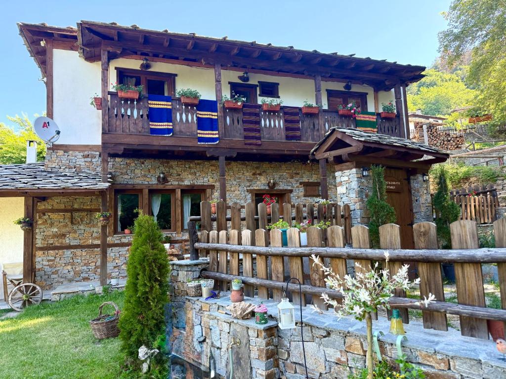 a stone house with a fence in front of it at Капсъзовата къща in Leshten