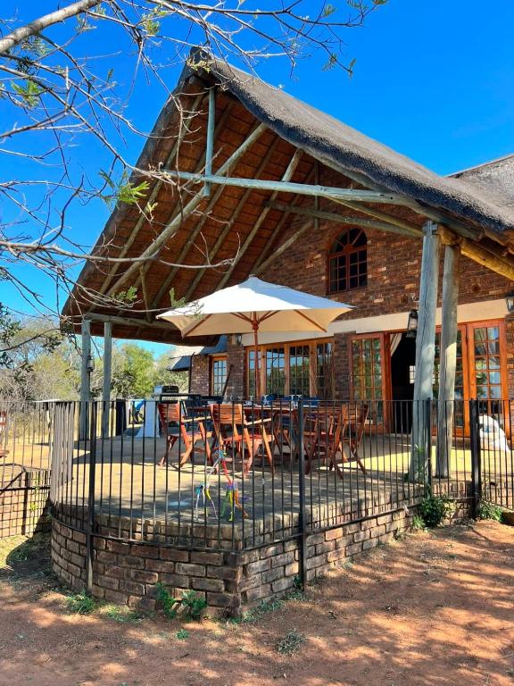 a building with tables and umbrellas in front of it at Kudu Plaas - Wildlife on your doorstep in Beestekraal