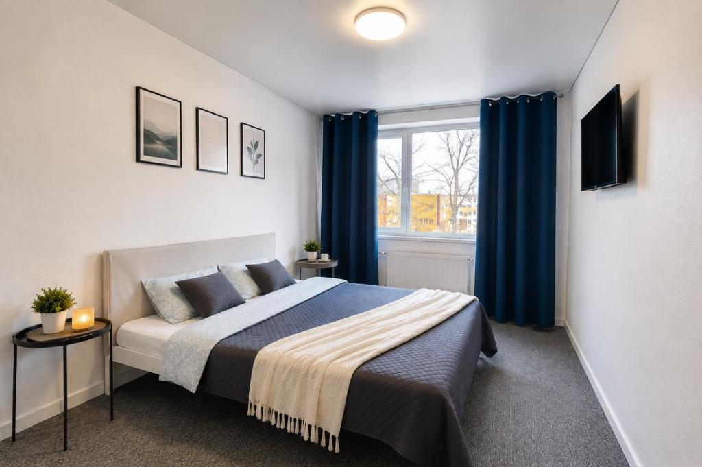 a bedroom with a bed with blue curtains and a window at Kivi Apartments in Jõhvi