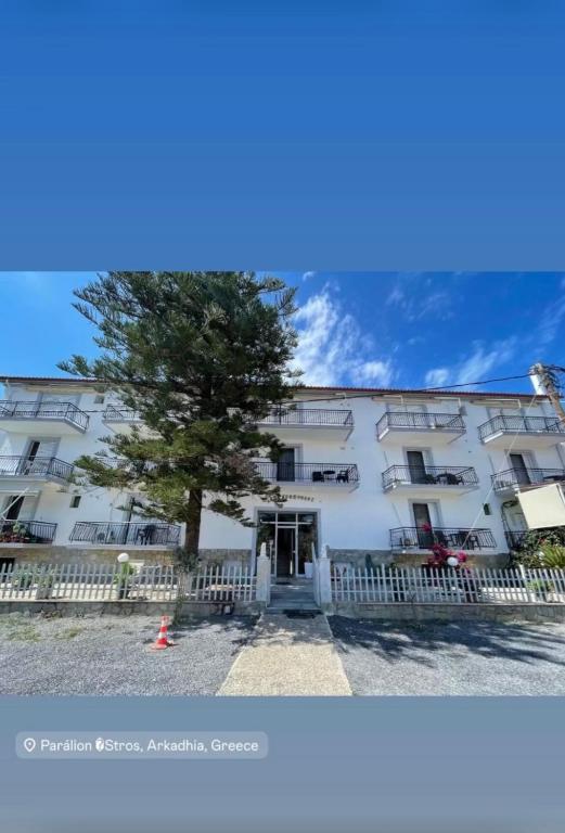 a large white building with a tree in front of it at Argiropouloi in Paralio Astros