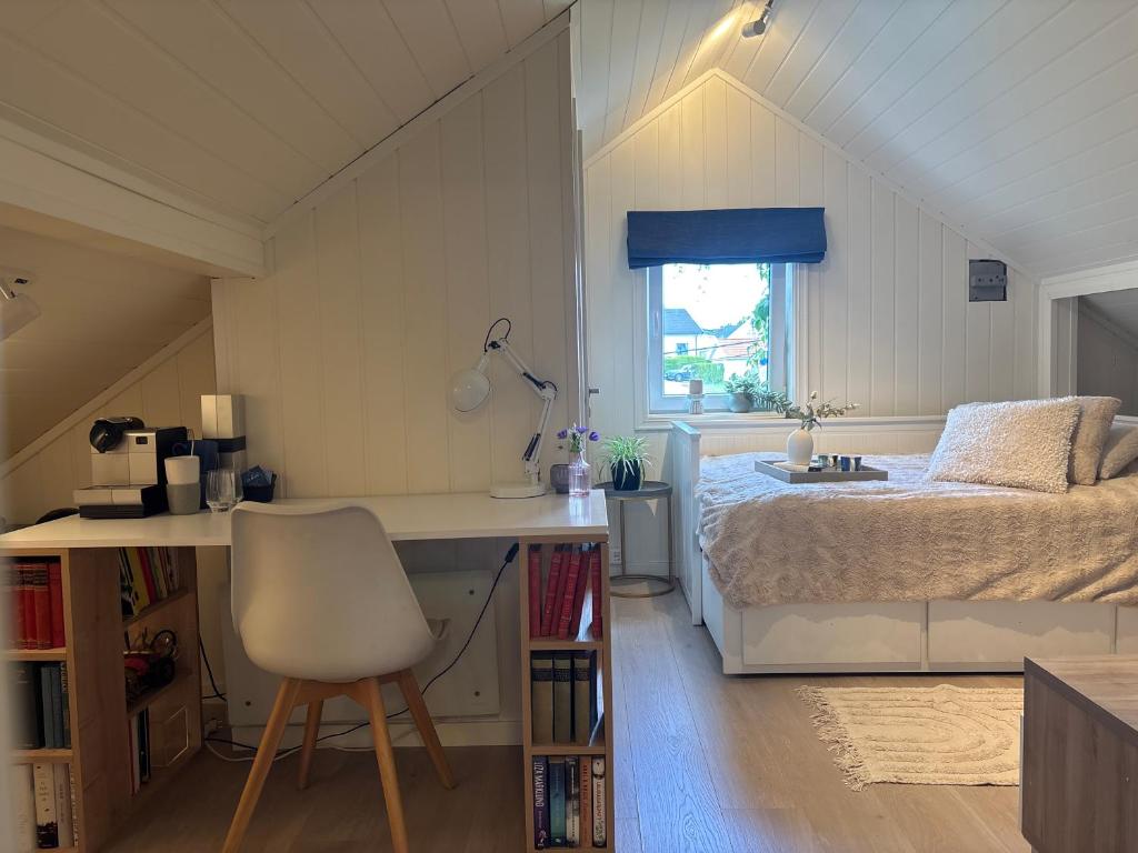 a bedroom with a bed and a desk and a chair at Loftsrom in Drammen