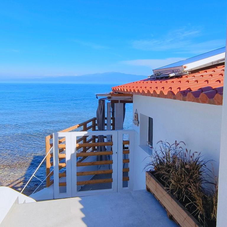 a white house with a staircase next to the ocean at Lighthouse in Kallirákhi
