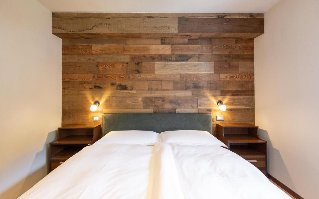 a bedroom with a wooden accent wall and a bed at Appartamento Petit Flower in Valdidentro