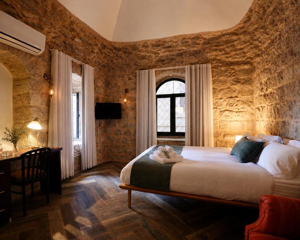 a bedroom with a large bed in a stone wall at Petrakis Inn in Jerusalem