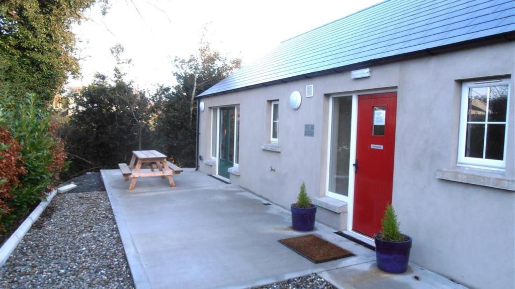 a small house with a red door and a bench at Ballyvoy Camping Barn in Willenhall