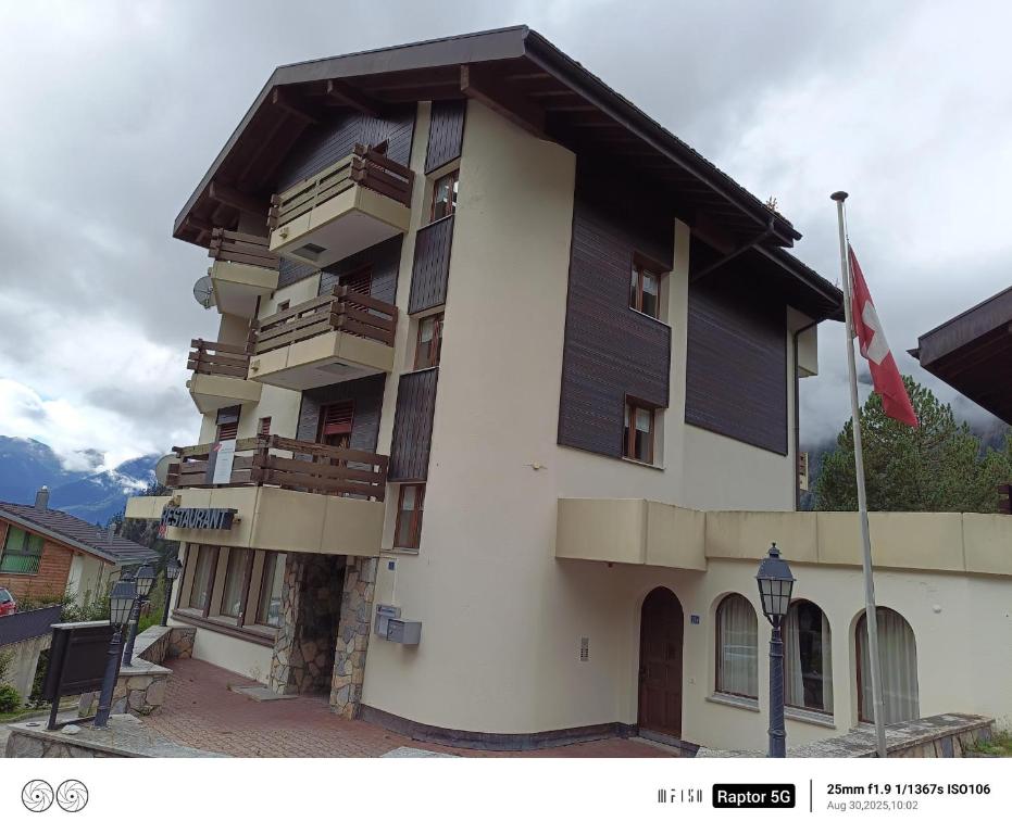 a building with wooden balconies and a flag at Haus Belstar B in Naters
