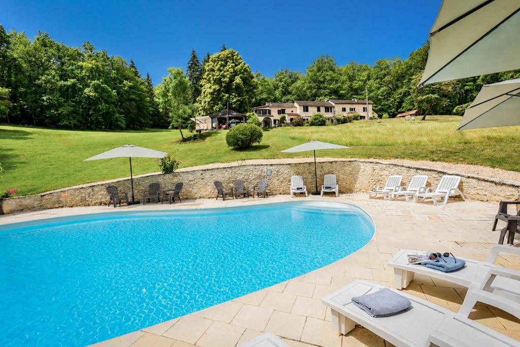 a pool with chairs and umbrellas in a yard at Font Neuve in Souillac