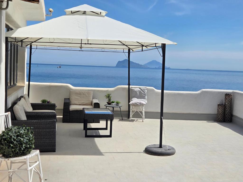 a large white umbrella on a patio with the ocean at Hotel Odissea in Canneto