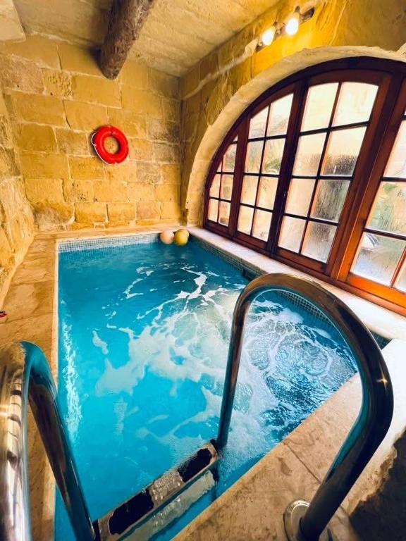 a large swimming pool in a room with a window at Mithna farmhouse in Għarb