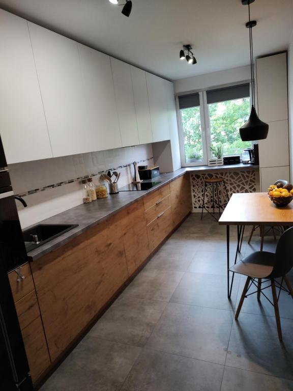 a kitchen with wooden cabinets and a table and a window at Apartament Przyjaźń in Tarnowskie Góry