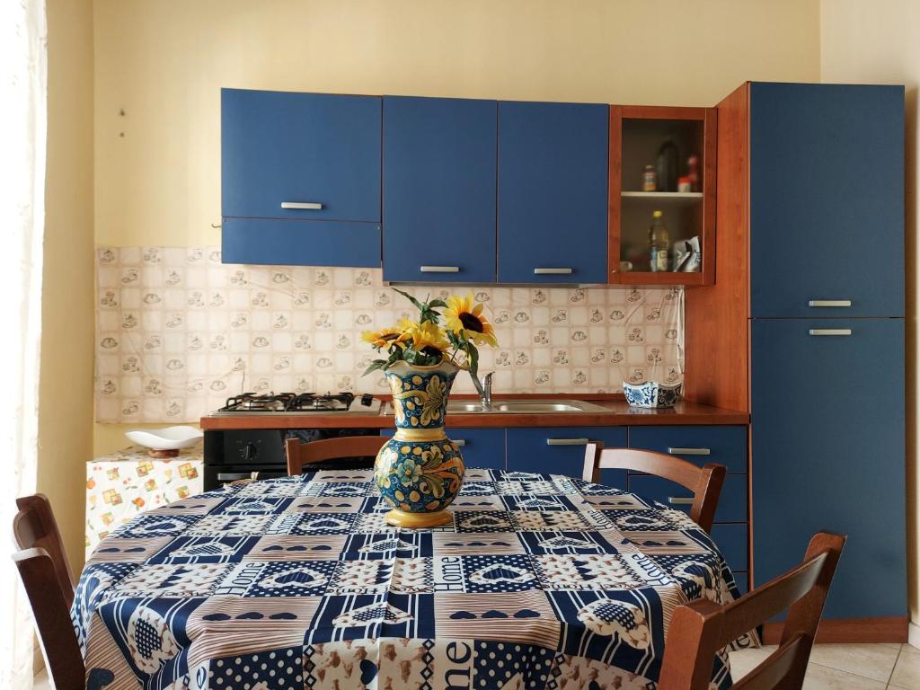 a kitchen with a table with a vase of flowers on it at Affitto breve Puccio A Chiazza Realmonte in Realmonte