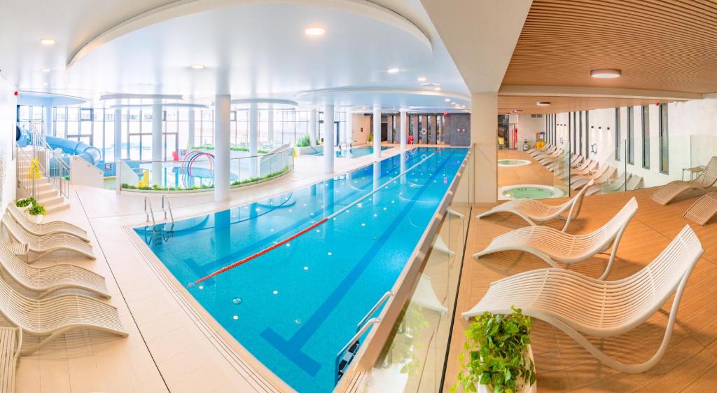 an indoor swimming pool with white chairs and a large swimming pool at Happy Land Aqua Polanki B407 in Kołobrzeg