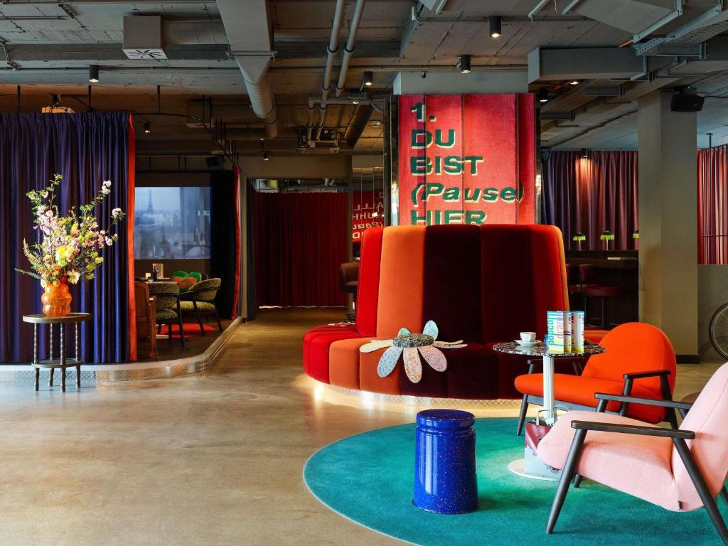 a lobby with a red couch and chairs and tables at 25hours Hotel beim MuseumsQuartier in Vienna