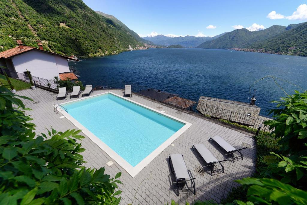 a swimming pool with chairs and a view of a lake at Residence degli Oleandri APP A1 in Argegno
