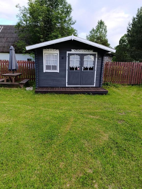 a black tiny house with a picnic table in a yard at Kolkja Holiday Centre -Kolkja Puhkeküla in Kolkja