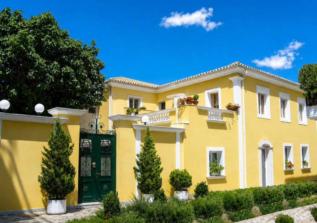 a yellow house with a green door and trees at Siena in Preveza