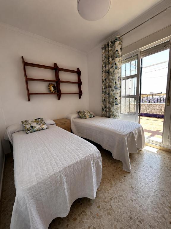 two beds in a room with a window at Brisa de Pinares in Barbate