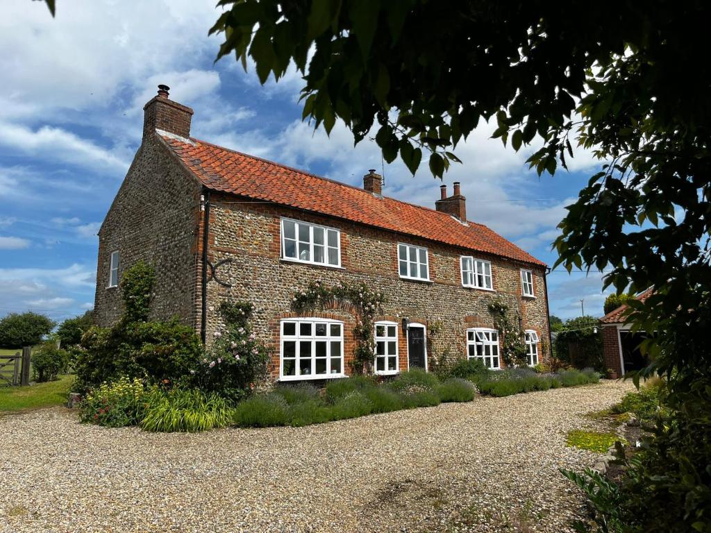 an old brick house with white windows and a gravel driveway at Garwood House in Holt