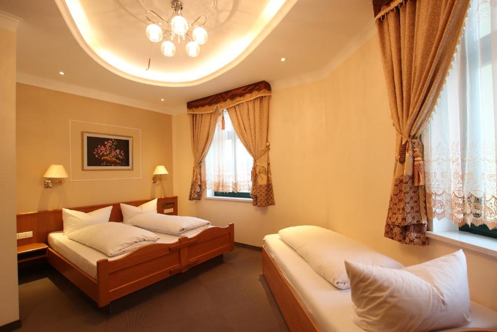 a bedroom with two beds and a window at Hotel Europäischer Hof in Elsterwerda
