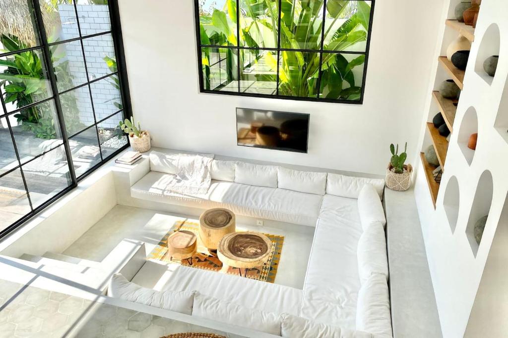 a living room with white furniture and large windows at The Young Villas - Canggu in Canggu