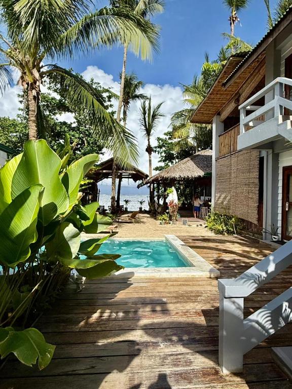 a house with a swimming pool next to the ocean at Happiness Beach Resort Siargao in General Luna
