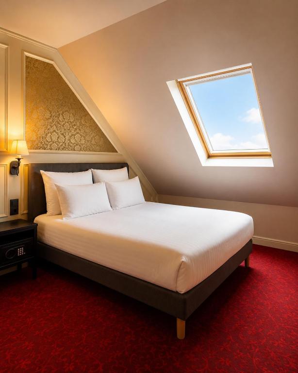 a bedroom with a large bed with a window at Hôtel Le Montmartre Saint Pierre in Paris