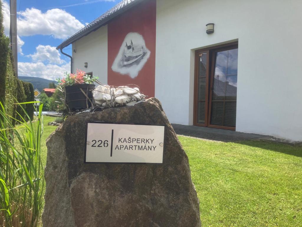 a sign on a rock in front of a house at Kašperky Apartmány in Kašperské Hory
