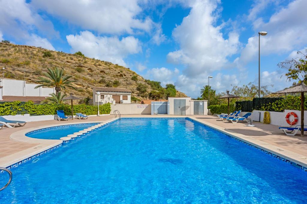 a swimming pool with chairs and a mountain in the background at Casa Nemo in Rojales