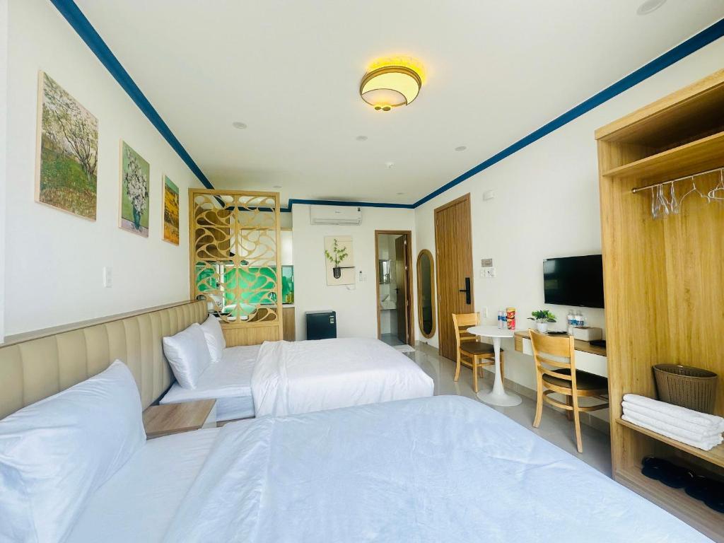 a hotel room with two beds and a desk at Lighthouse Hotel & Apartment Phan rang in Kinh Dinh