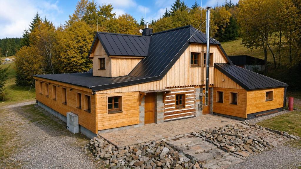 a house with a black roof on top of a stone wall at Bouda Ticha in Dolní Malá Úpa