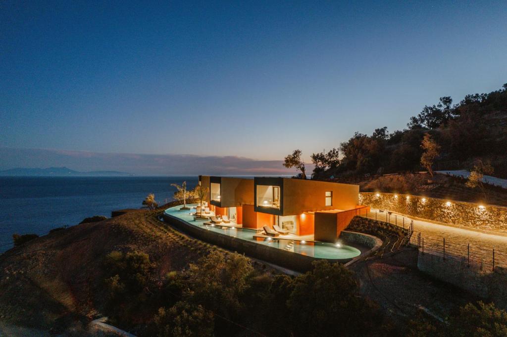 a house on a hill with lights on it at River Villas Plomari - Luxury Villas with Direct Pool Access in Plomari