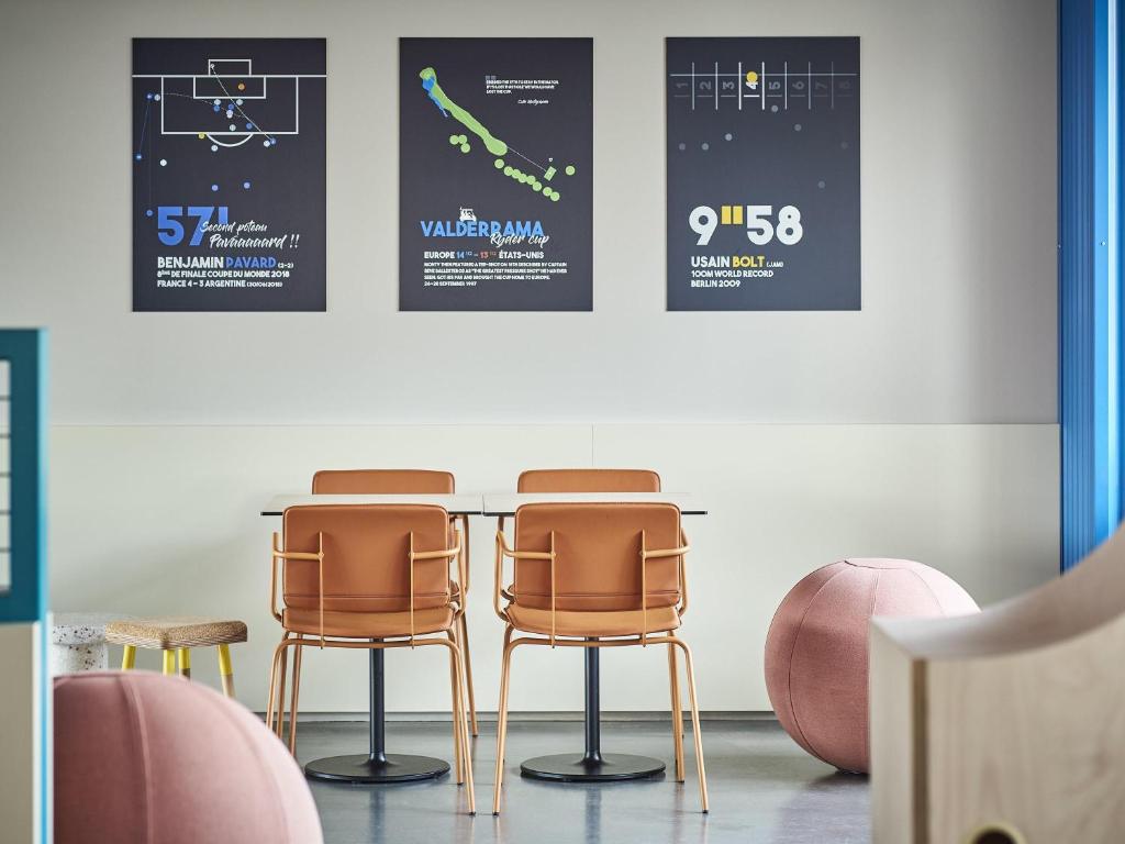 a table and chairs in a room with posters at ibis budget Nancy Laxou in Nancy