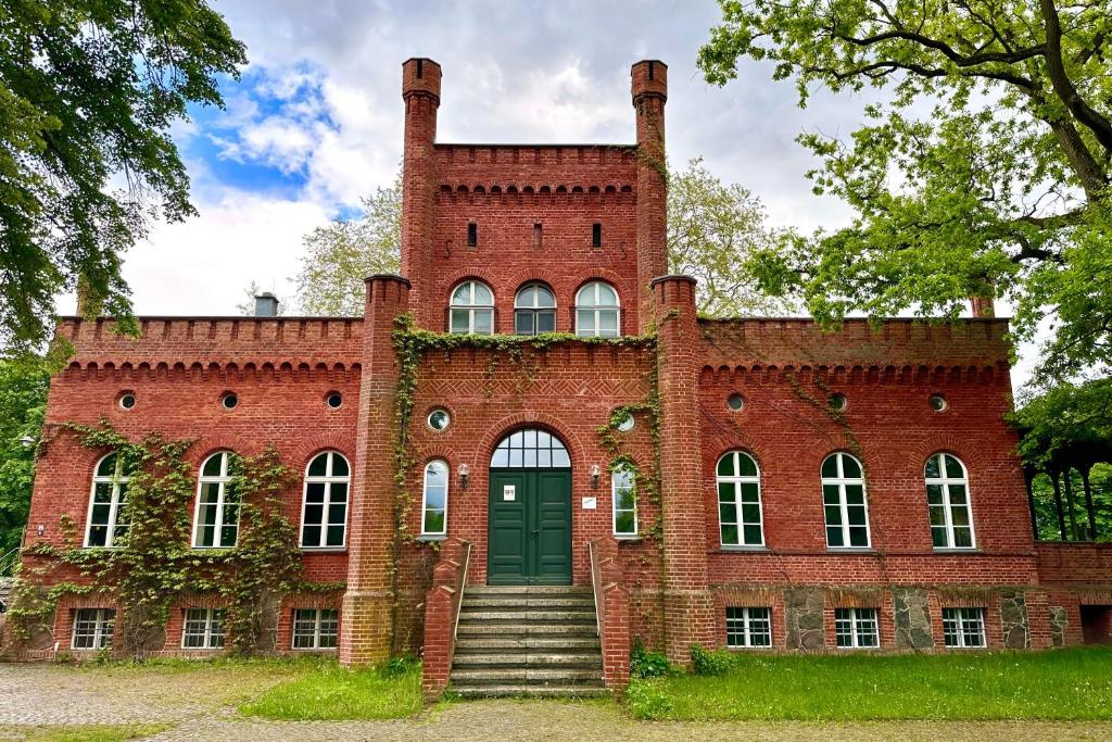 an old red brick building with a green door at Herrenhaus Libnow in Murchin