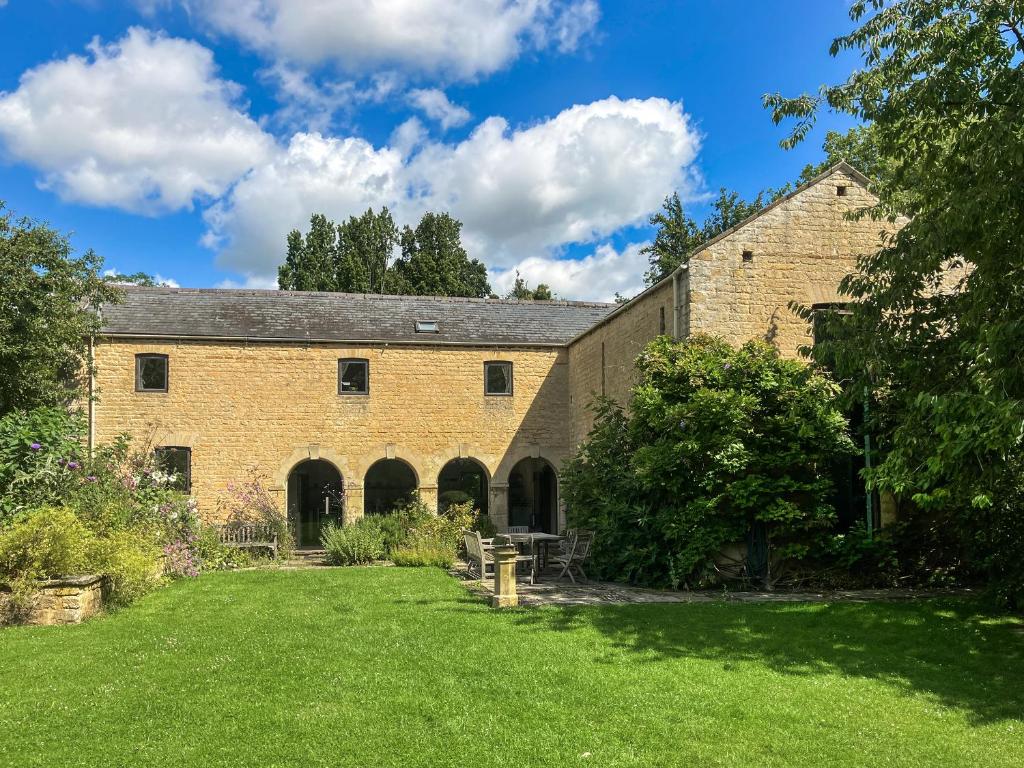 an old brick building with a grass yard at The Barn - Uk51594 in Grantham