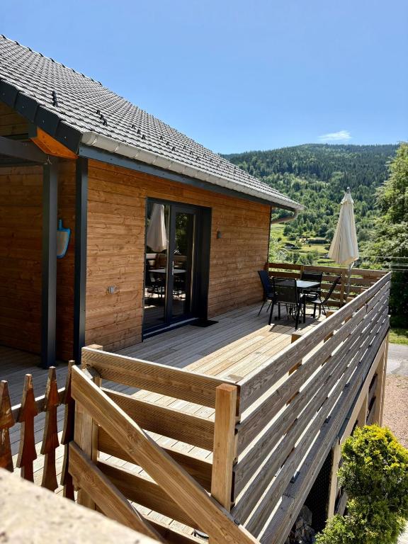 a house with a wooden deck with a table and chairs at Chalet Iris, spa privatif, 4p in Rochesson
