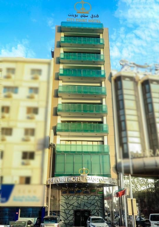 a tall building with a sign in front of it at City Point Hotel in Manama